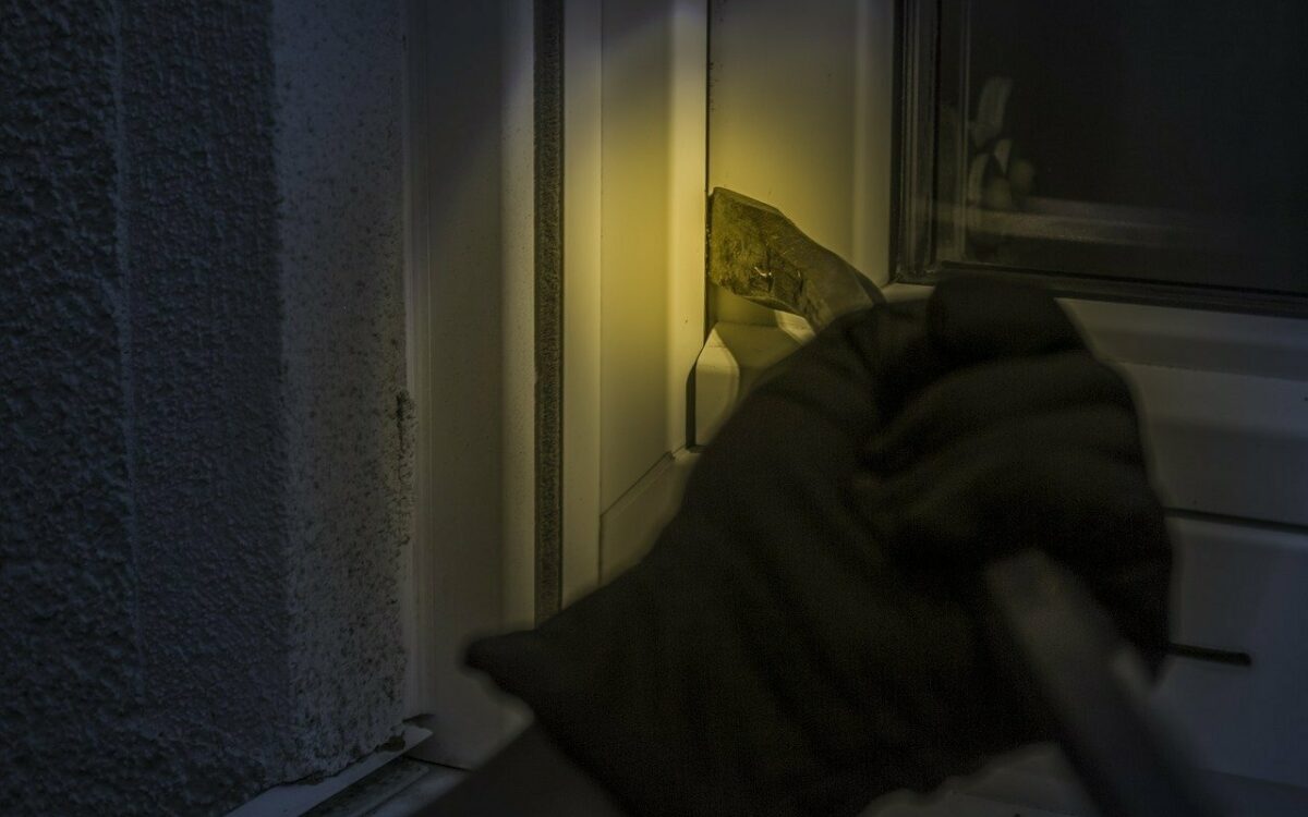 Ein Einbrecher versucht nachts ein Fenster zu knacken Ein Einbrecher versucht nachts ein Fenster zu knacken